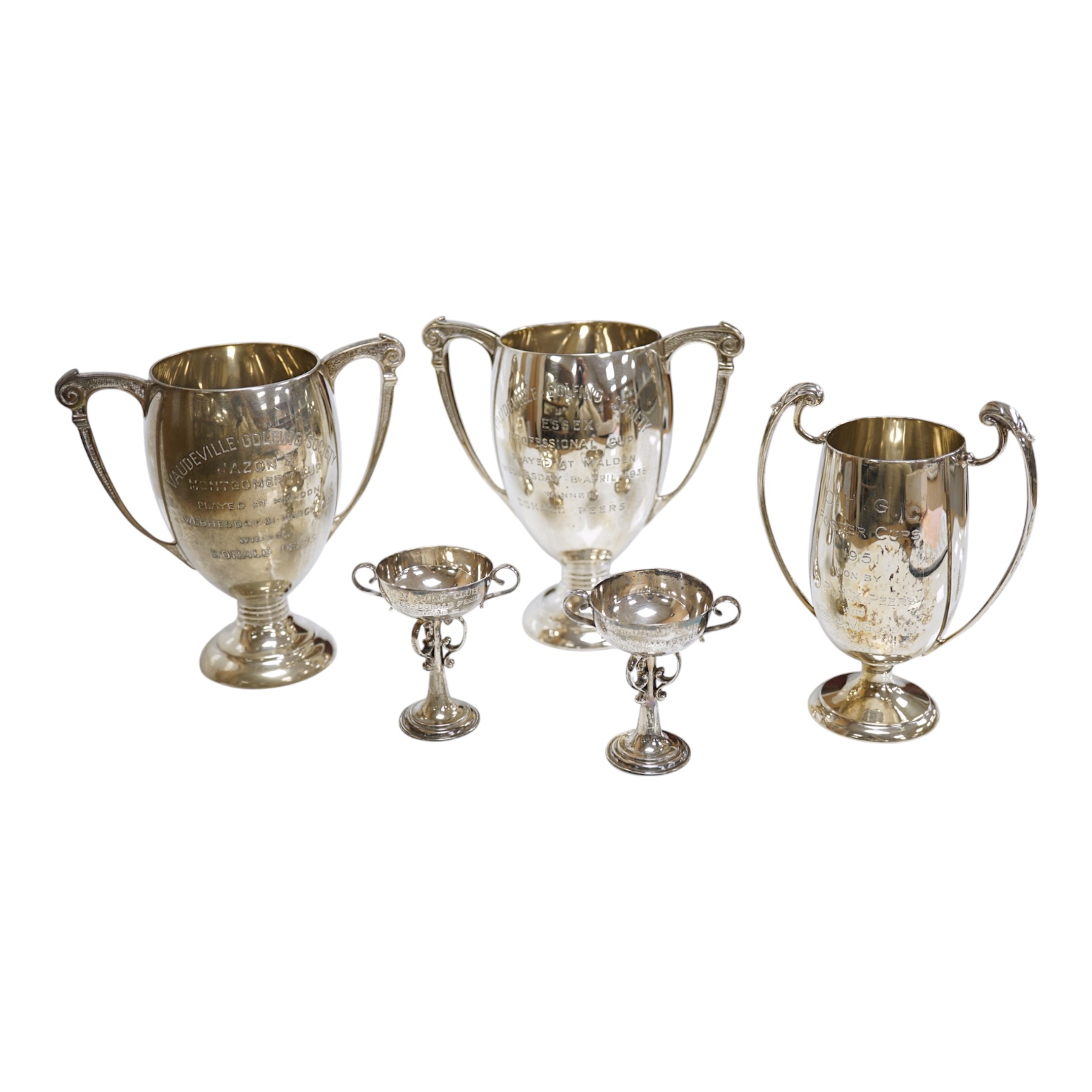 Five assorted small silver trophy cups including a pair by Edward Barnard & Sons, London, 1936, 12.7cm, 20.5cm. Condition poor to fair